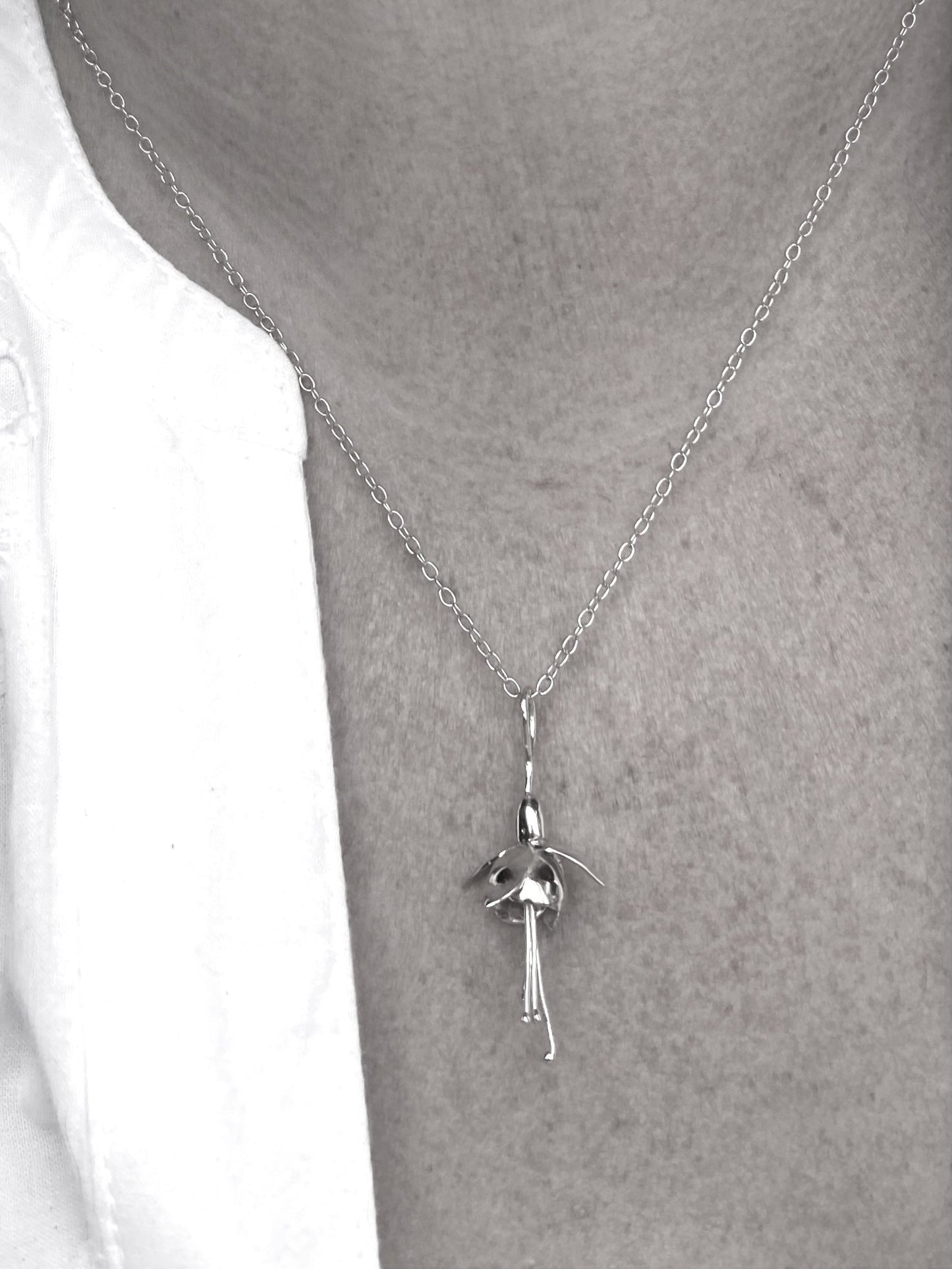 black and white photo of gold fuchsia pendant on neck