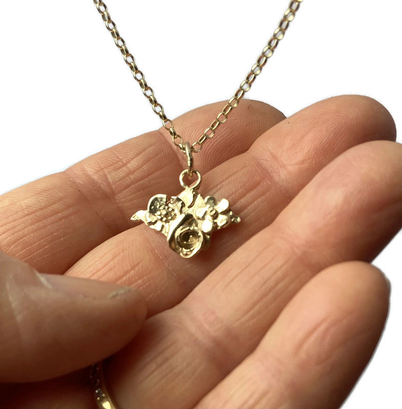Gold floral Isle of Wight silhouette pendant and chain on fingers