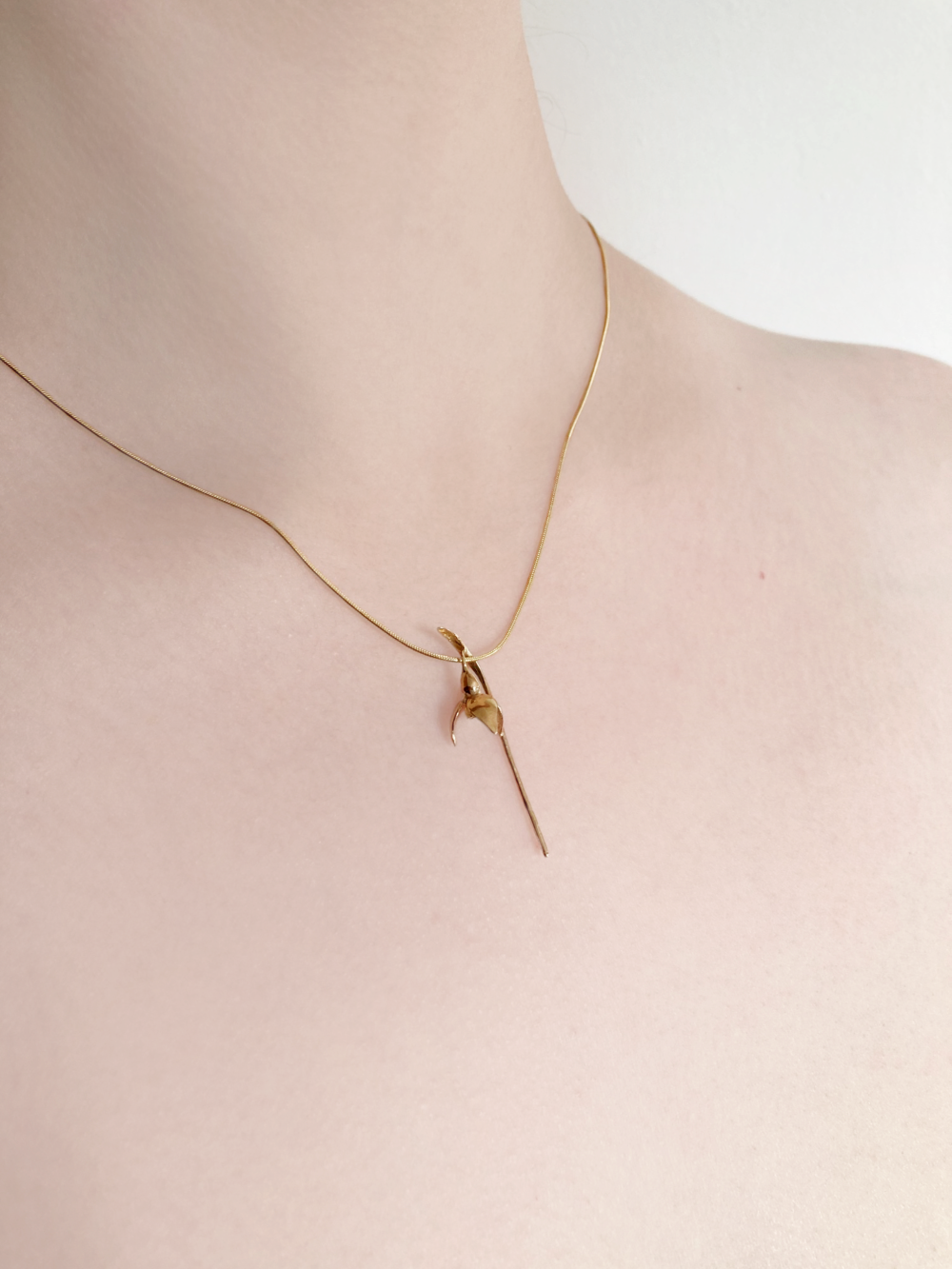 woman's neck wearing gold chain with lifelike gold single snowdrop pendant