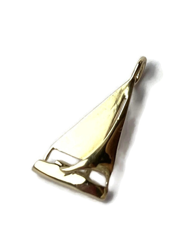 A polished gold pendant shaped like a sailboat, shown on a plain white background with a soft drop shadow.