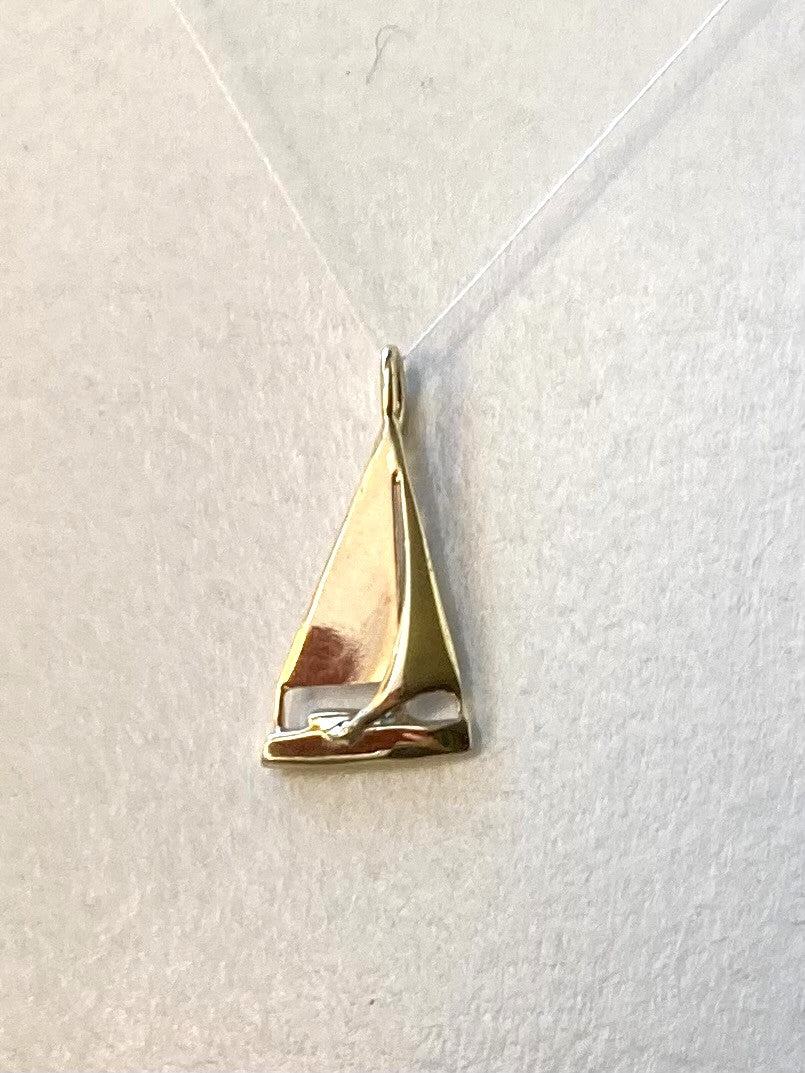 A polished gold sailing yacht pendant, shown on a grey background with a soft drop shadow.