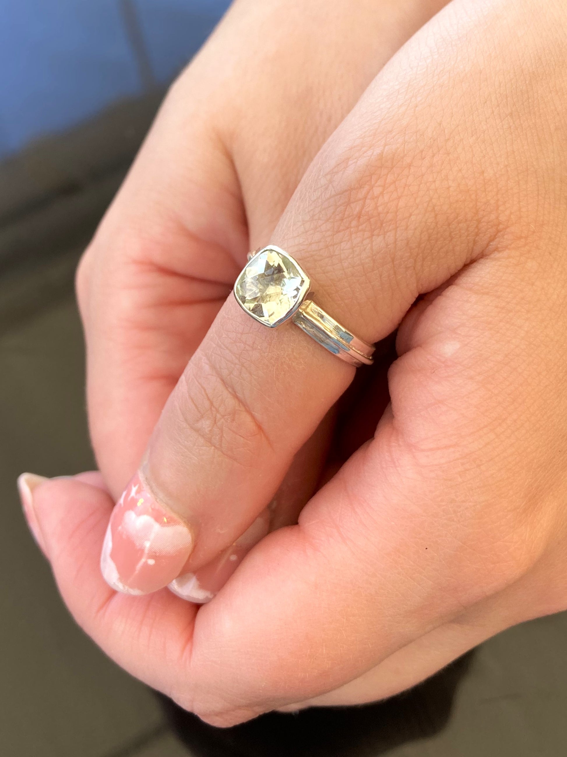 silver ring with big green gemstone, worn on clasping hands