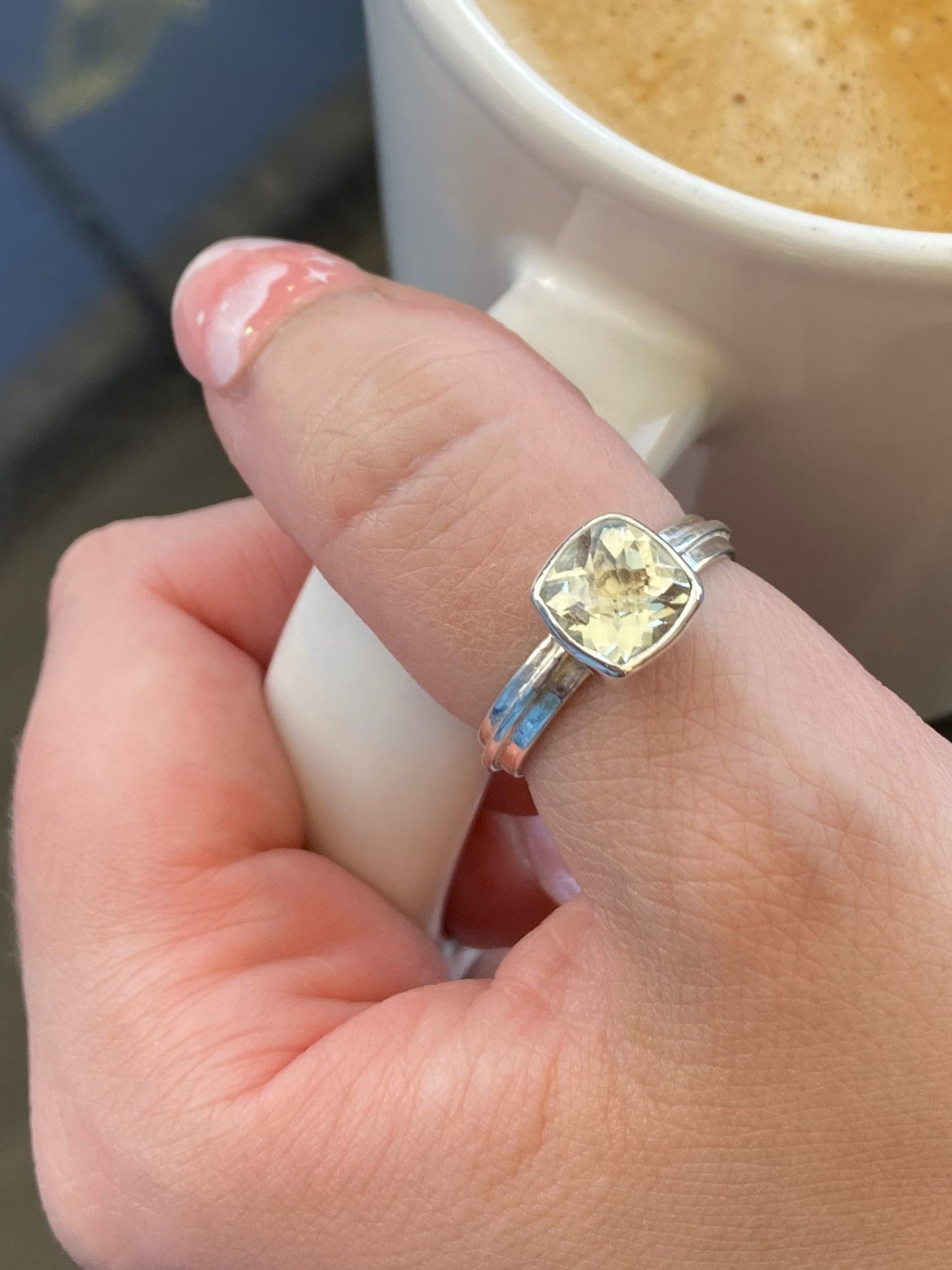 square pale green gemstone on silver band ring, worn on hand holding mug