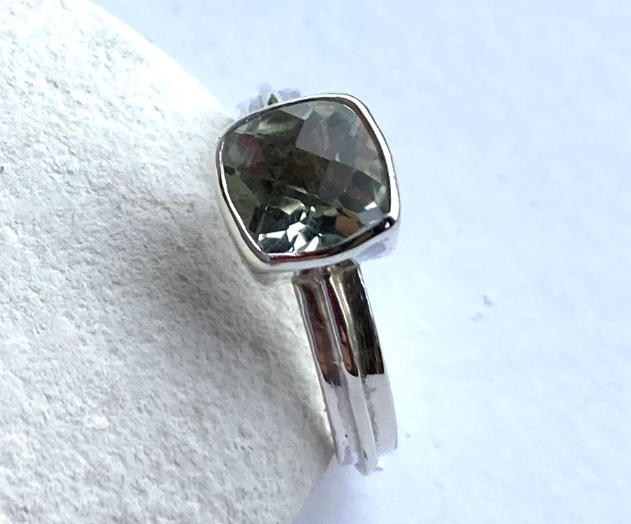 green amethyst silver ring leaning on white pebble