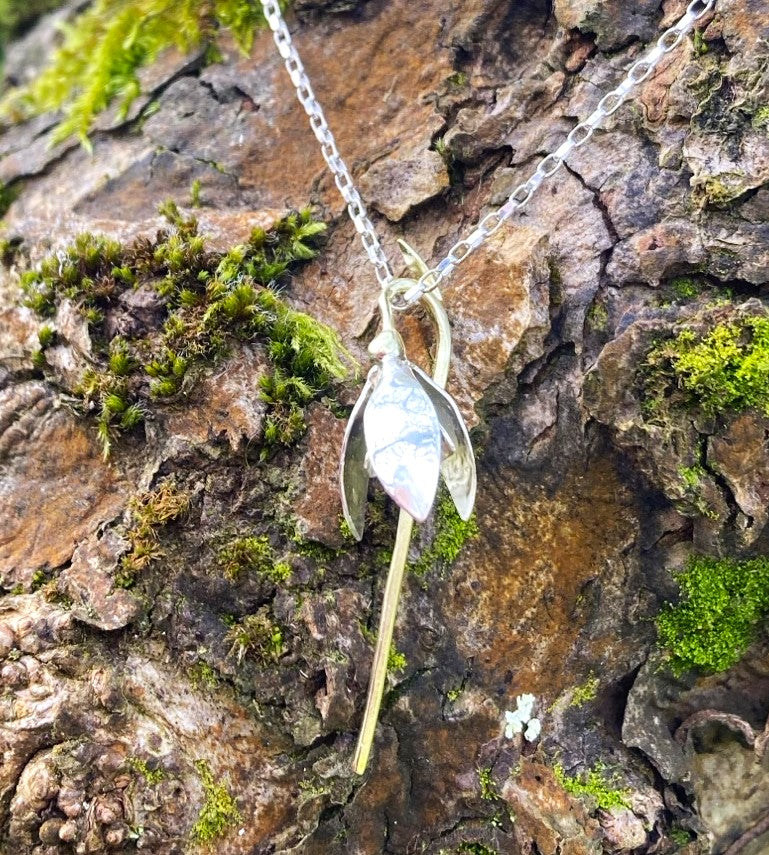 snowdrop pendant in white and green gold, on tree bark