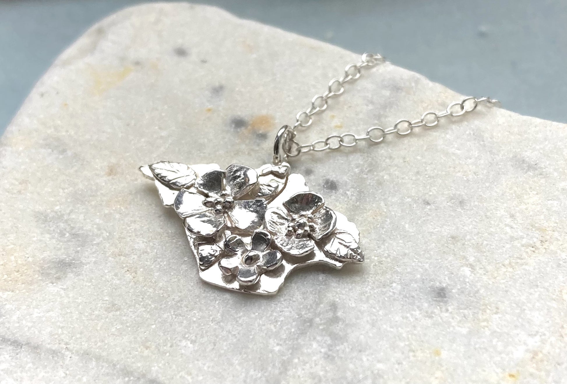 Isle of White shape pendant with flower decoration by Kim Styles Jewellery, on marble background 