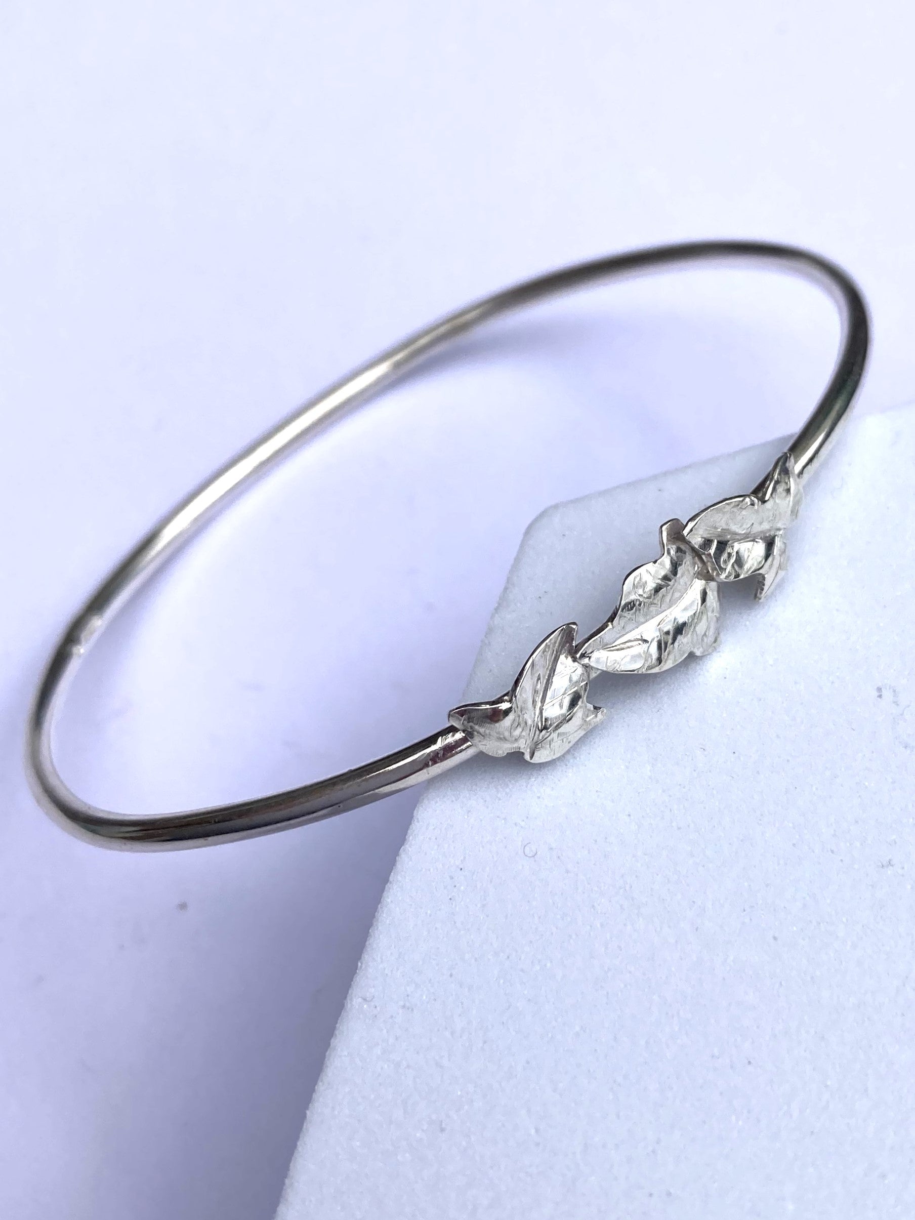 slim bangle with three detailed ivy leaves, on grey background
