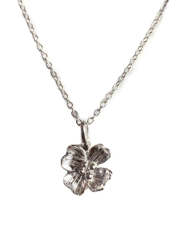 A silver Dogwood flower pendant necklace on a delicate silver chain, shown against a plain white background.
