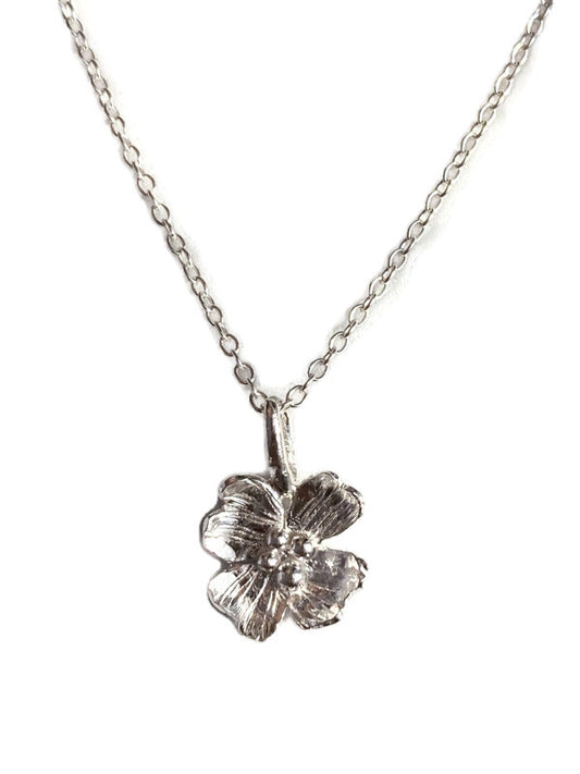 A silver Dogwood flower pendant necklace on a delicate silver chain, shown against a plain white background.