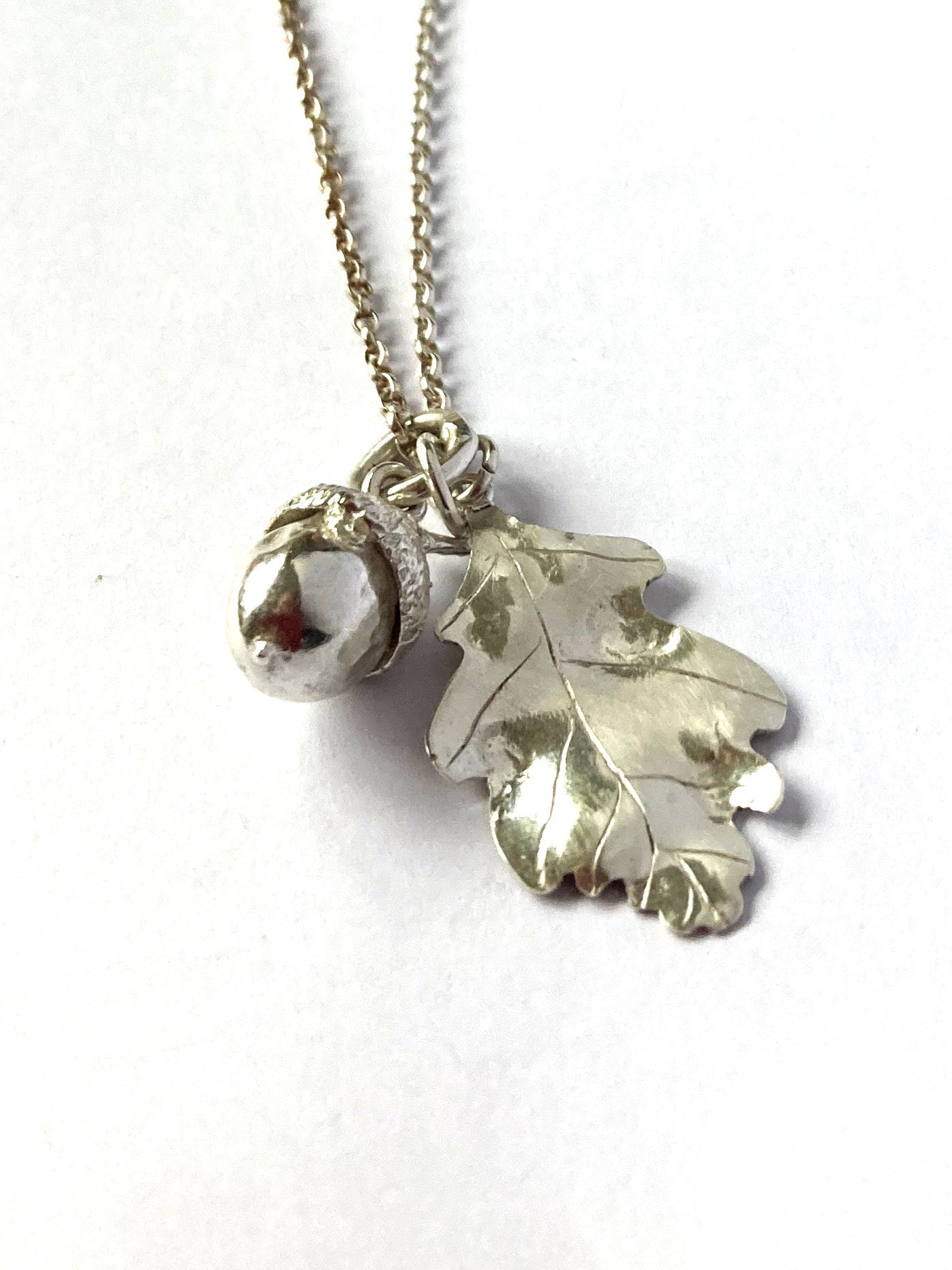 Botanical tiny acorn and oak leaf pendant hand made in sterling silver by Isle of Wight jeweller Kim Styles