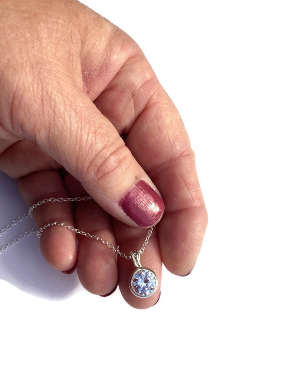 Kim Styles round silver solitaire sparkling pendant set in silver, held in hand