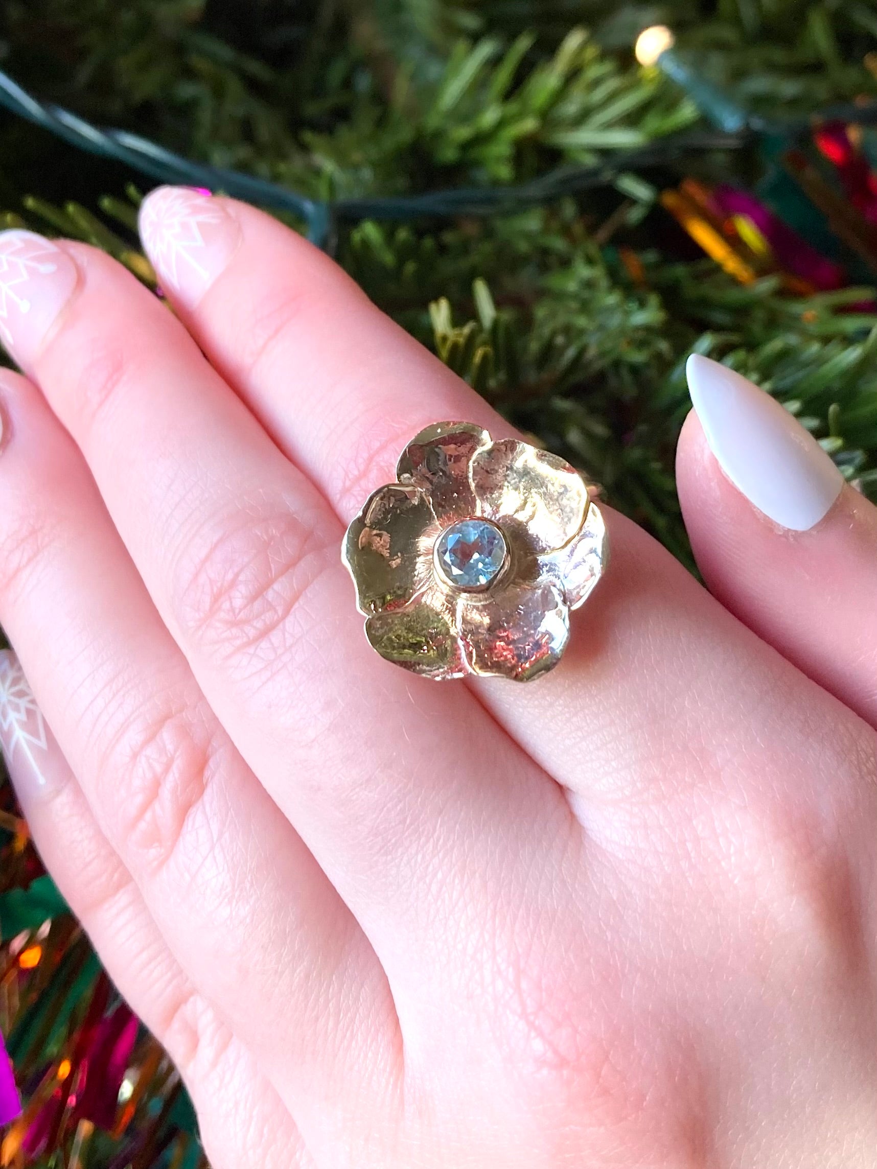large gold rose cocktail ring set with round blue topaz gemstone, on hand