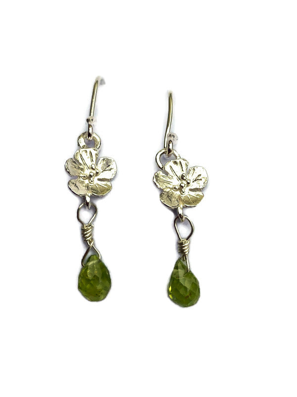 A pair of dangle earrings featuring textured  flower charms and faceted green teardrop peridot gemstones, shown against a plain white background.