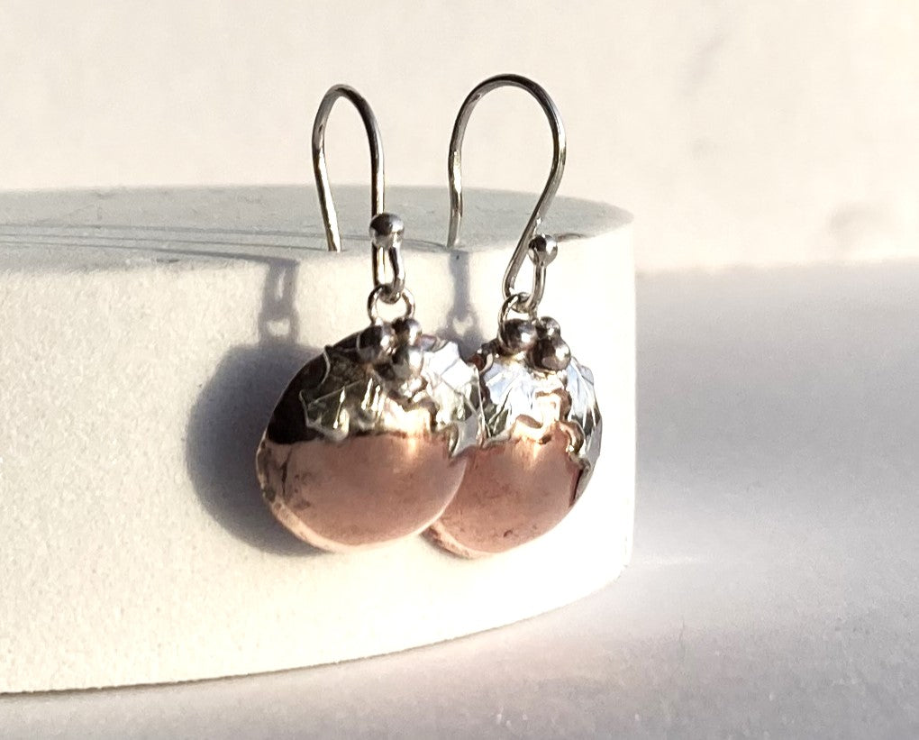 Christmas pudding theme earrings in silver and copper with tiny holly leaves, on white block