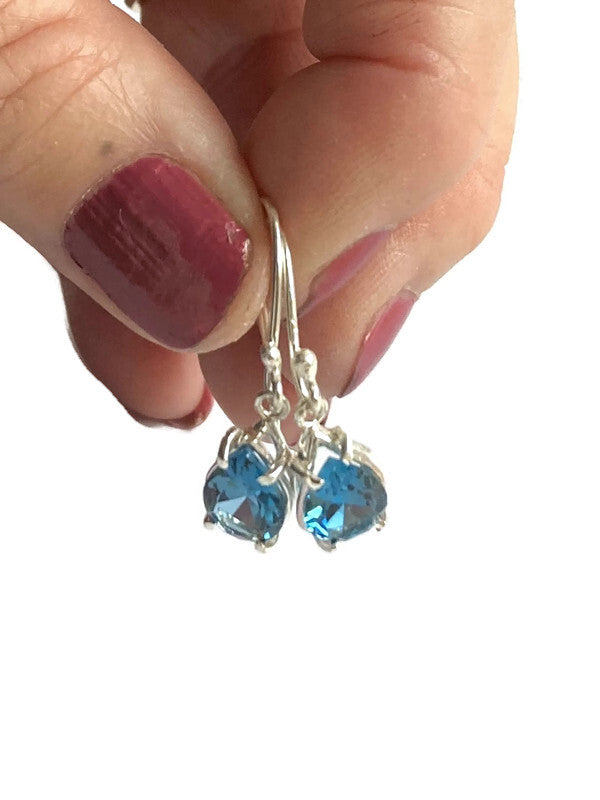 hand holding pear shape London blue topaz drop earrings on white background