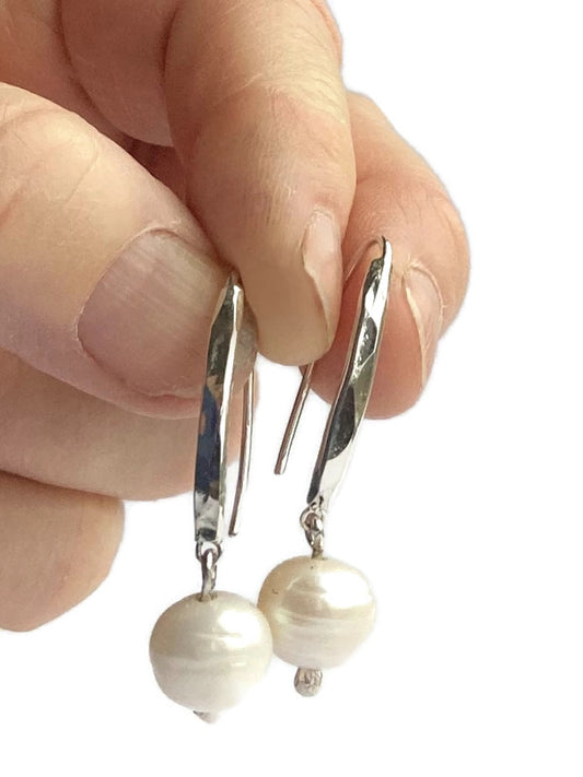 white pearl and bar drop earrings held in fingers