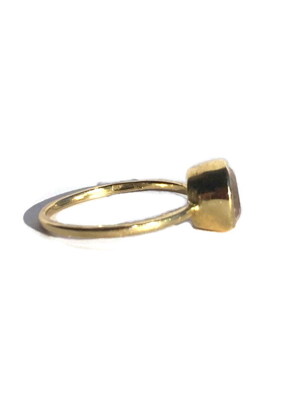Gold ring with a round cut gemstone on a white background