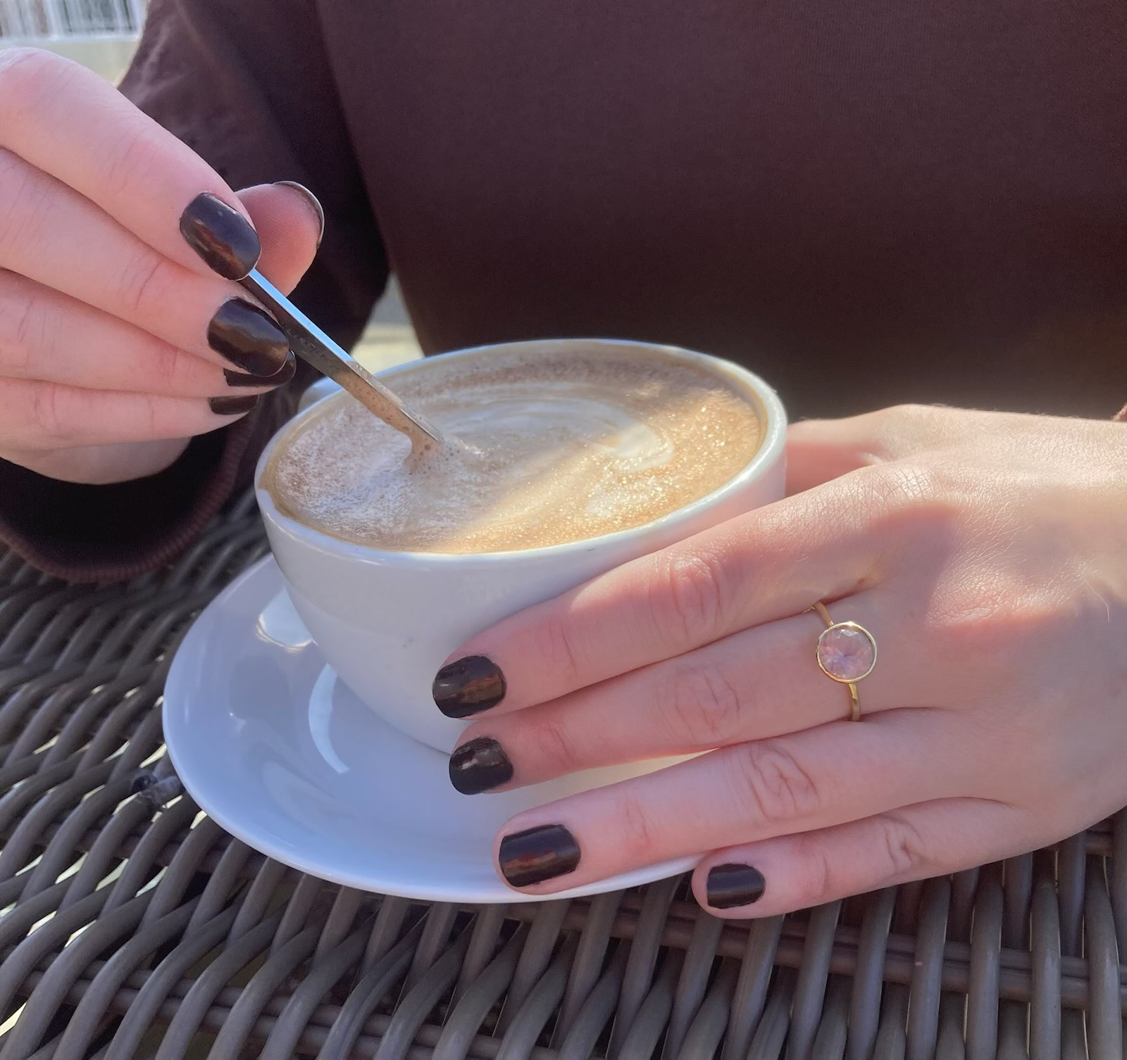 woman stirring cappuccino wearing 18ct Gold solitaire ring with a pale pink gemstone by Kim Styles Jewellery