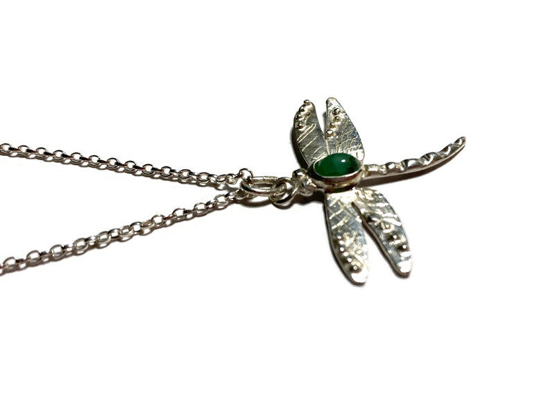 Silver dragonfly pendant with oval green cabochon emerald gemstone on a white background