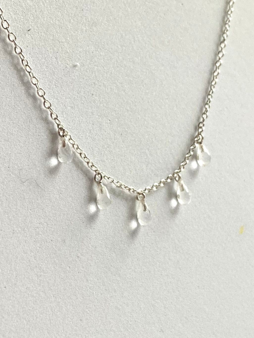 Silver necklace with teardrop-shaped pendants on a light gray background