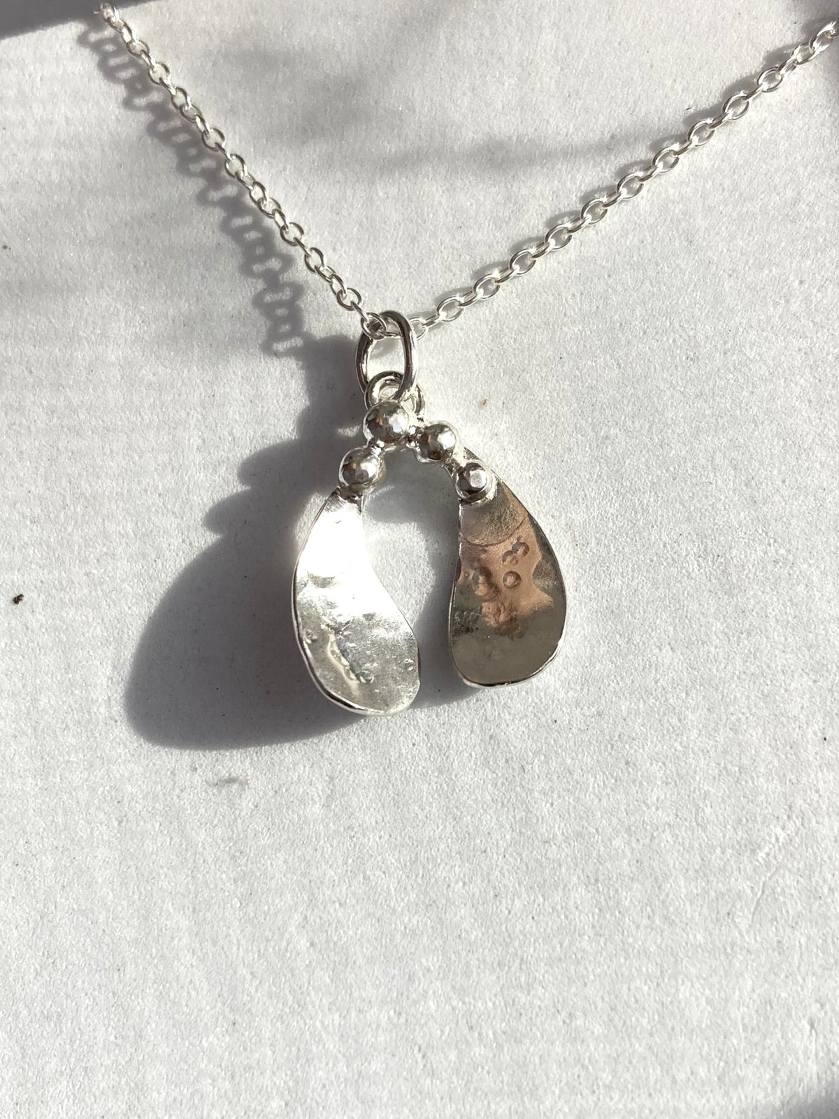 Sterling silver handmade mistletoe leaf pendant with berries, on a silver chain, on a grey background