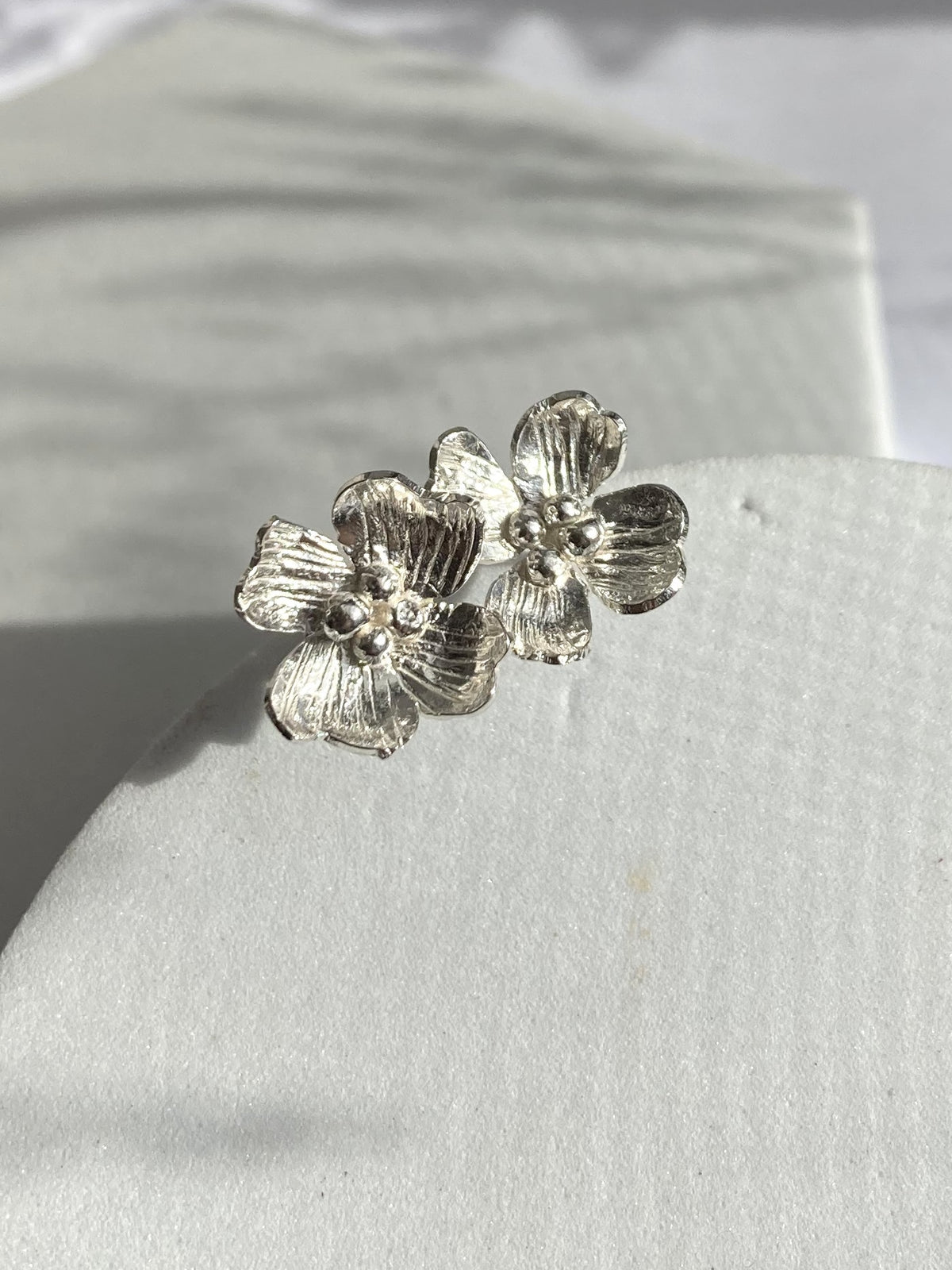 A pair of silver Dogwood flower-shaped stud earrings by Kim Styles Jewellery, displayed on a textured white surface.