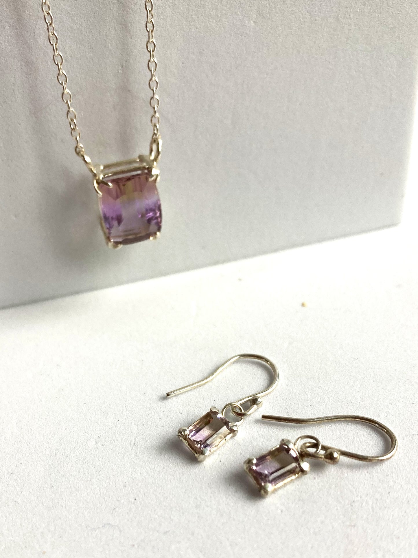 Kim Styles jewellery set with a oblong necklace and earrings featuring purple yellow ametrine  gemstones on a white background.