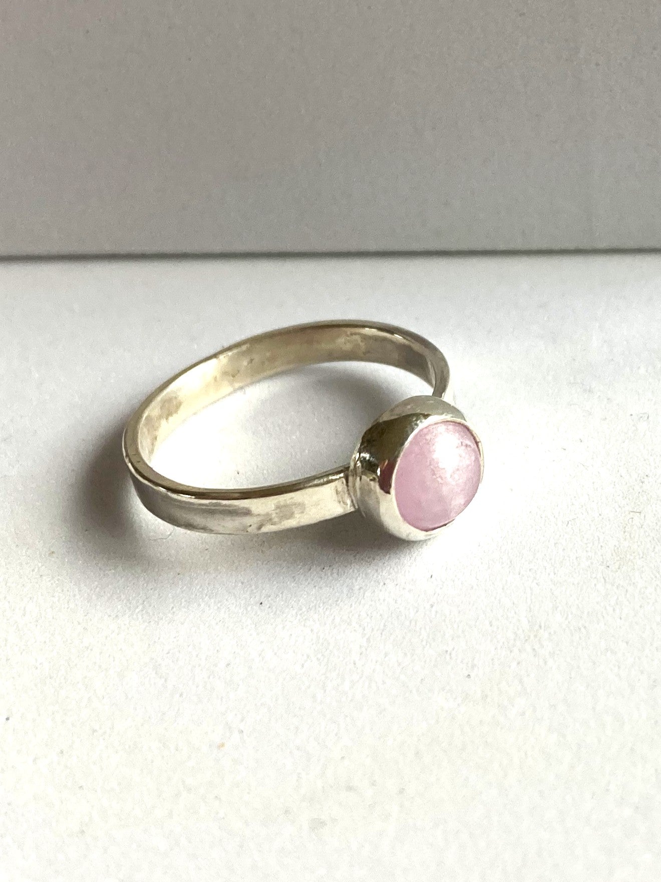 Silver ring with a pink cabochon gemstone on a white background