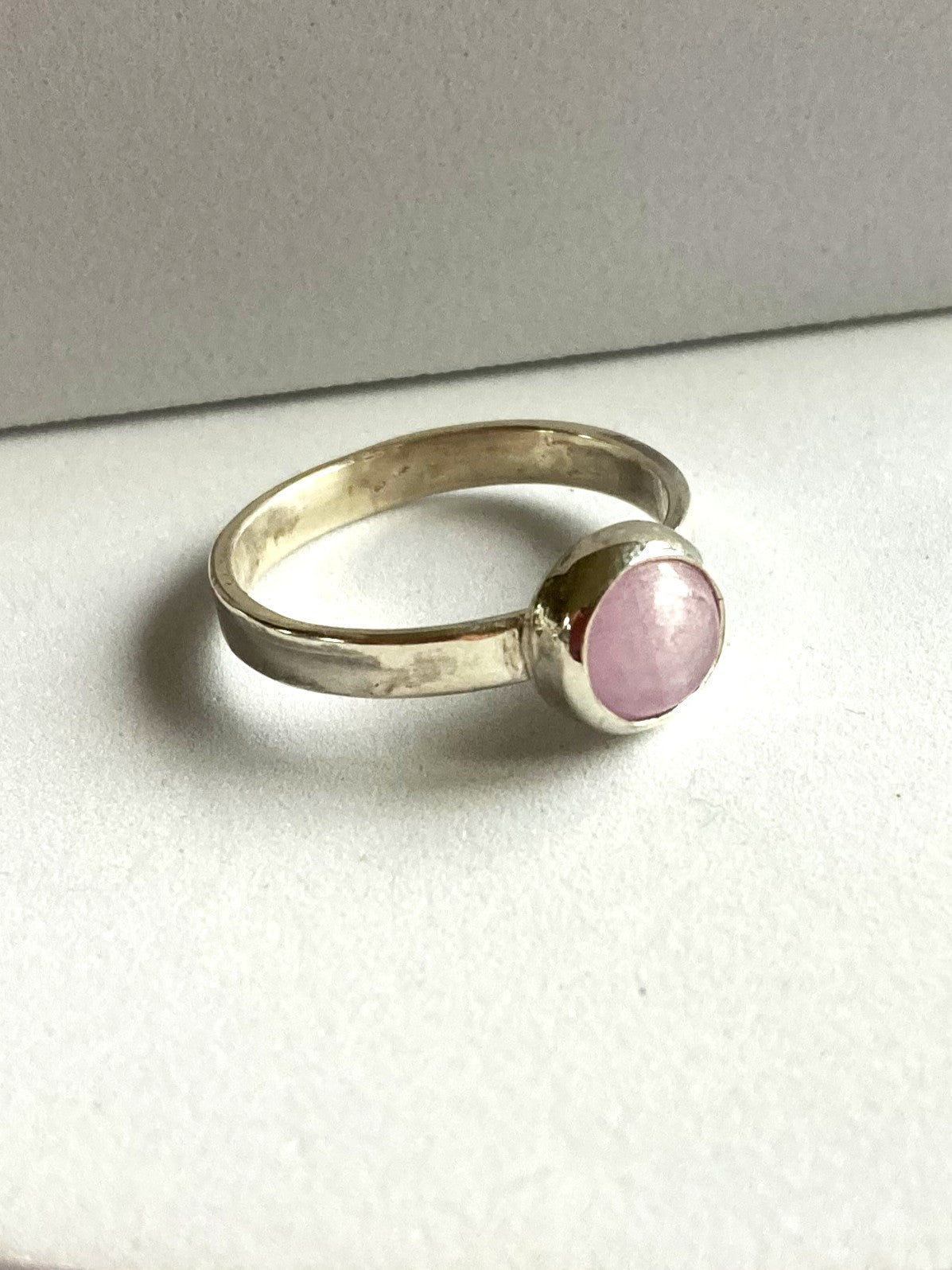 Silver solitaire ring with a pink kunzite gemstone on a white background