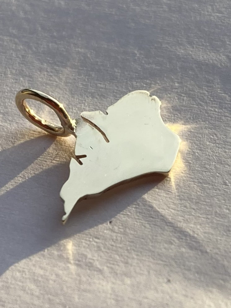 Gold pendant shaped like a map of the Isle of Wight by Kim Styles Jewellery on a textured surface