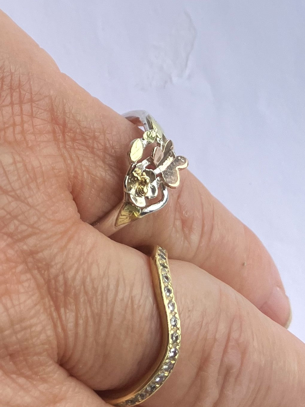 Handmade silver and gold butterfly garden ring with white gold flower, rose gold butterfly and green gold leaves, one-of-a-kind woodland inspired asymmetrical ring, worn on hand