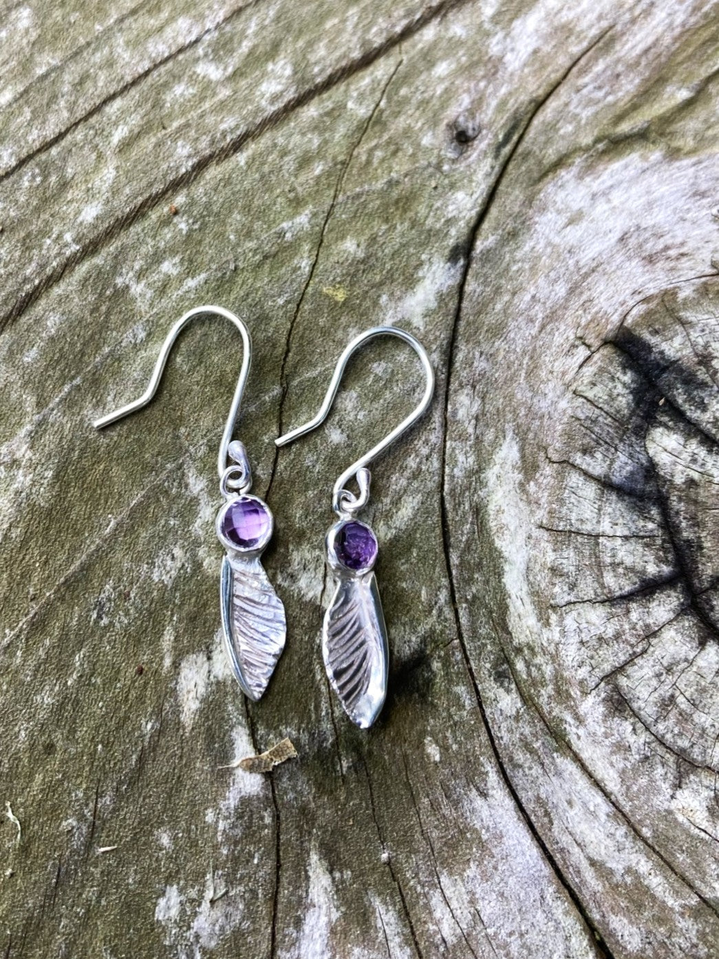 handmade textured  silver sycamore seed earrings by Kim Styles Jewellery set with round chequerboard cut amethysts, on textured wood background