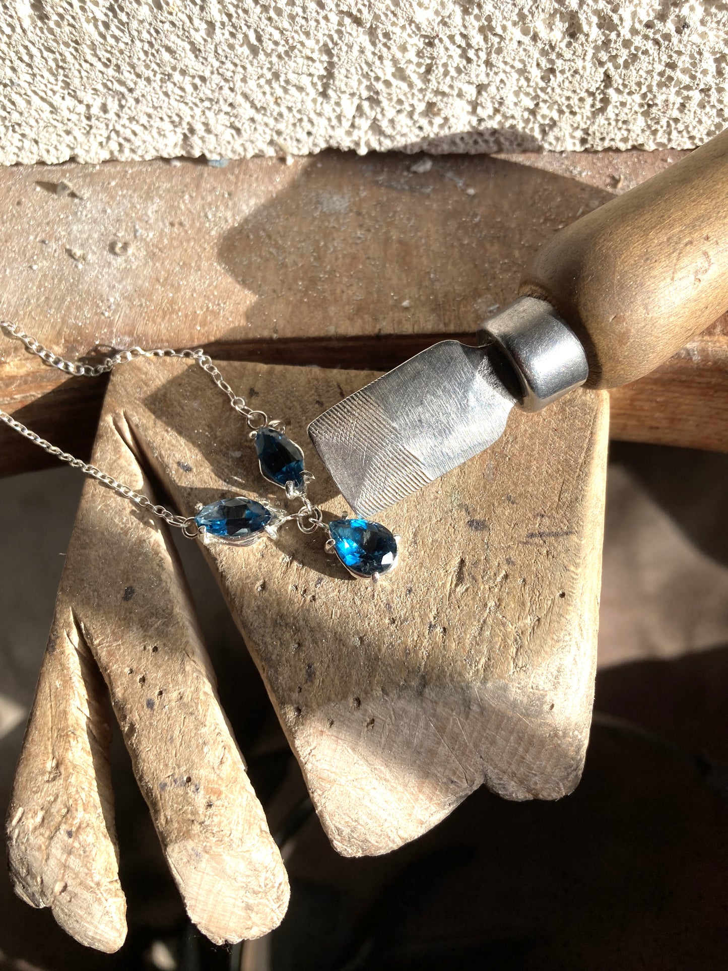 Kim Styles workbench with in progress necklace of London blue topaz stones on a wooden surface