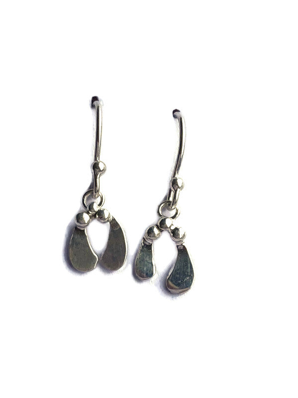 A pair of handmade silver dangle earrings with organic mistletoe leaf charms on a plain white background.