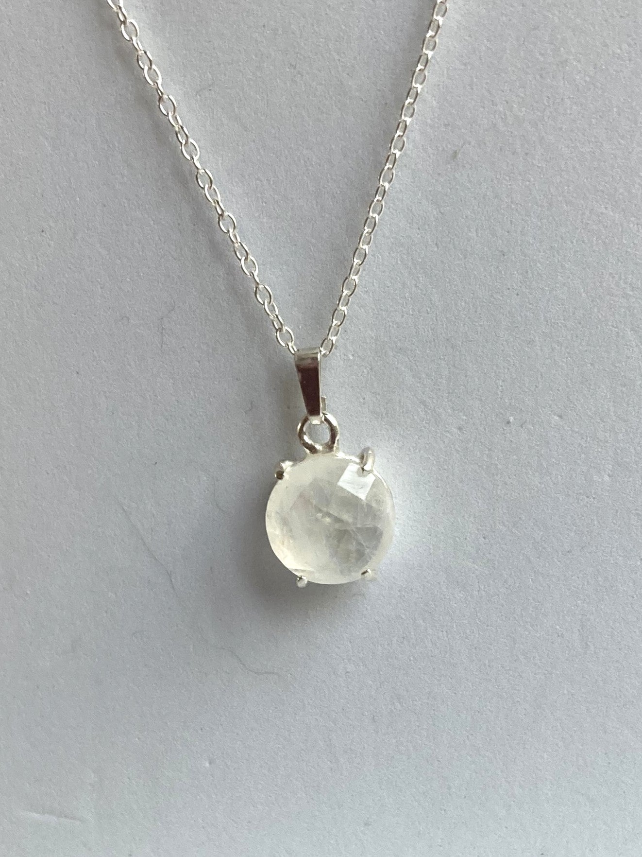 Necklace with a round chequerboard moonstone pendant on a light grey background