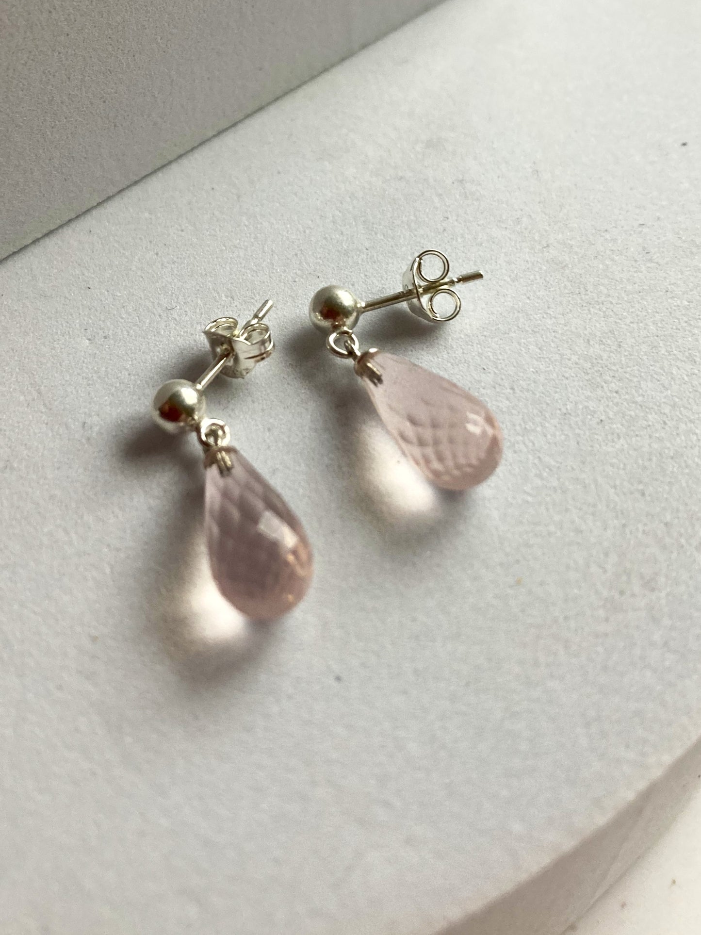 Pair of pink teardrop earrings on a light gray surface