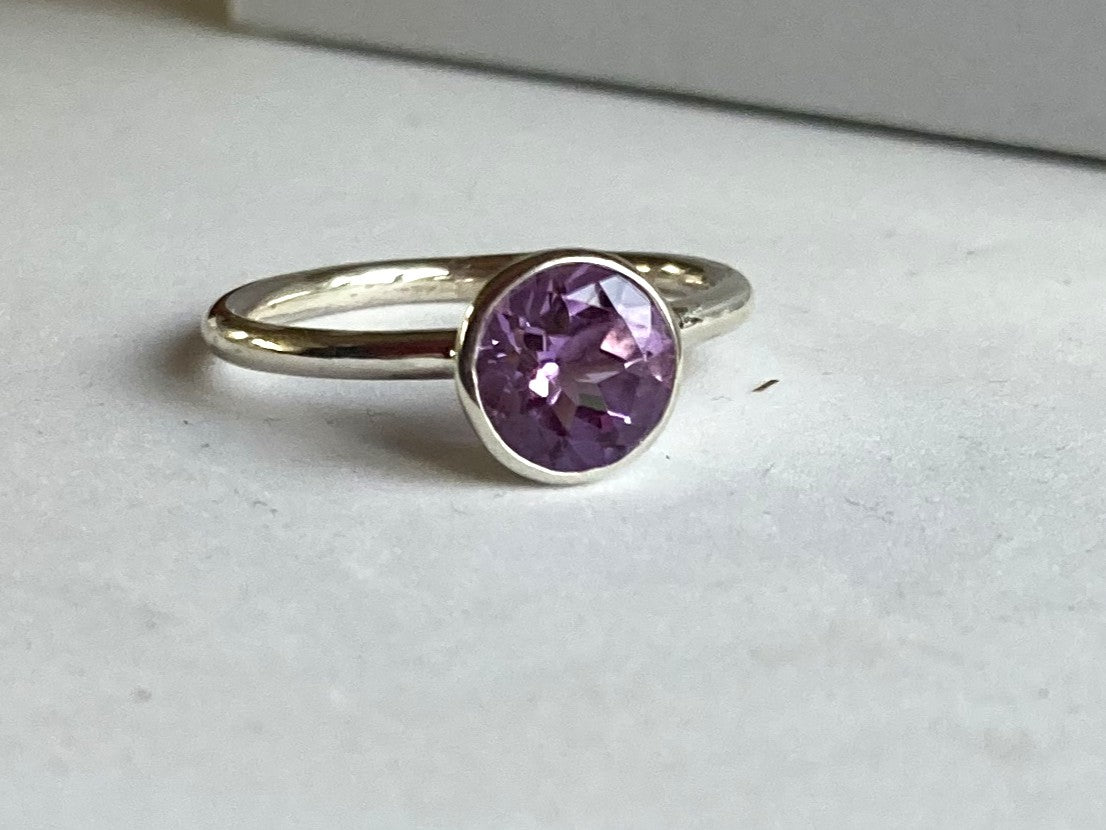 Kim Styles silver halo ring with a large round amethyst gemstone on a light grey surface