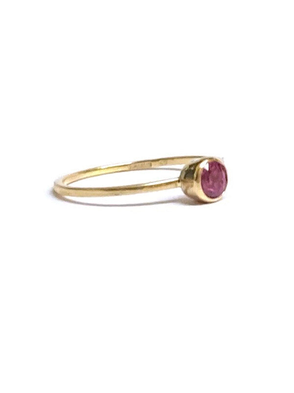 Slim gold ring with a round pink ruby gemstone in rub over setting, by Kim Styles Jewellery,  on a white background 