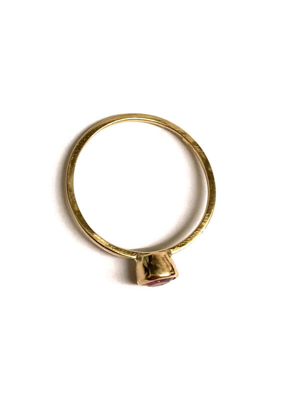 Gold ring with a solitaire gemstone on a white background