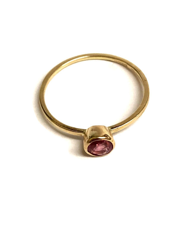 Kim Styles gold stacking solitaire ring with a pink gemstone on a white background