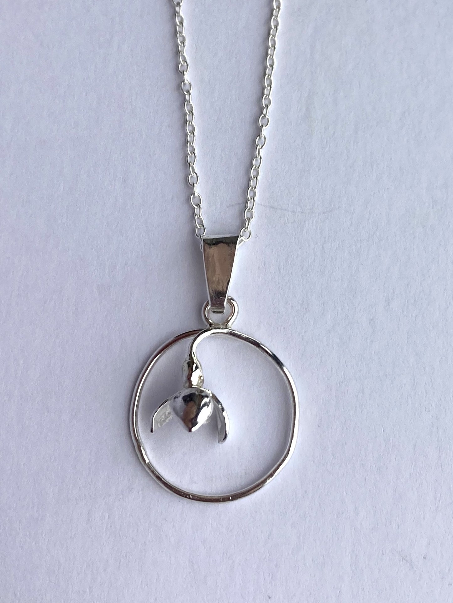small circle pendant with flower on grey background