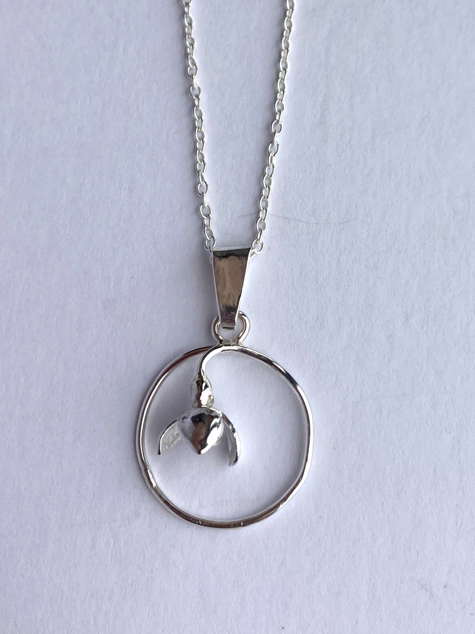 small circle pendant with flower on grey background