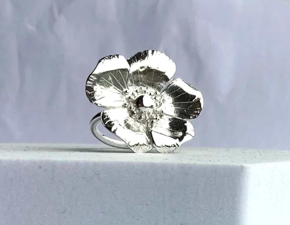 Large silver flower-shaped ring by Kim Styles Jewellery on a light grey background