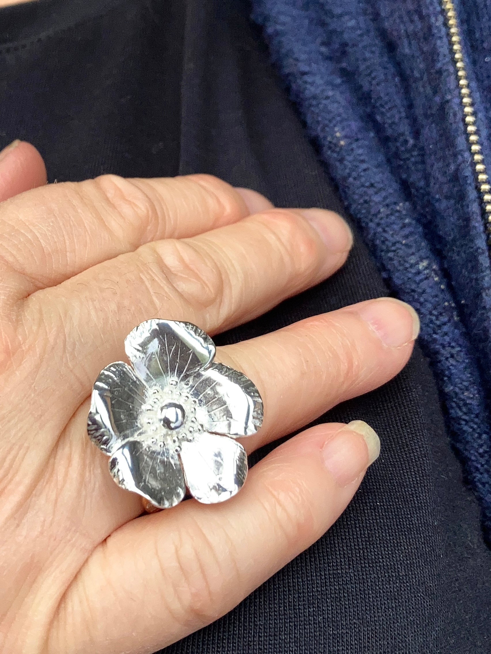 Chunk silver floral ring by Kim Styles Jewellery on a finger against a dark background