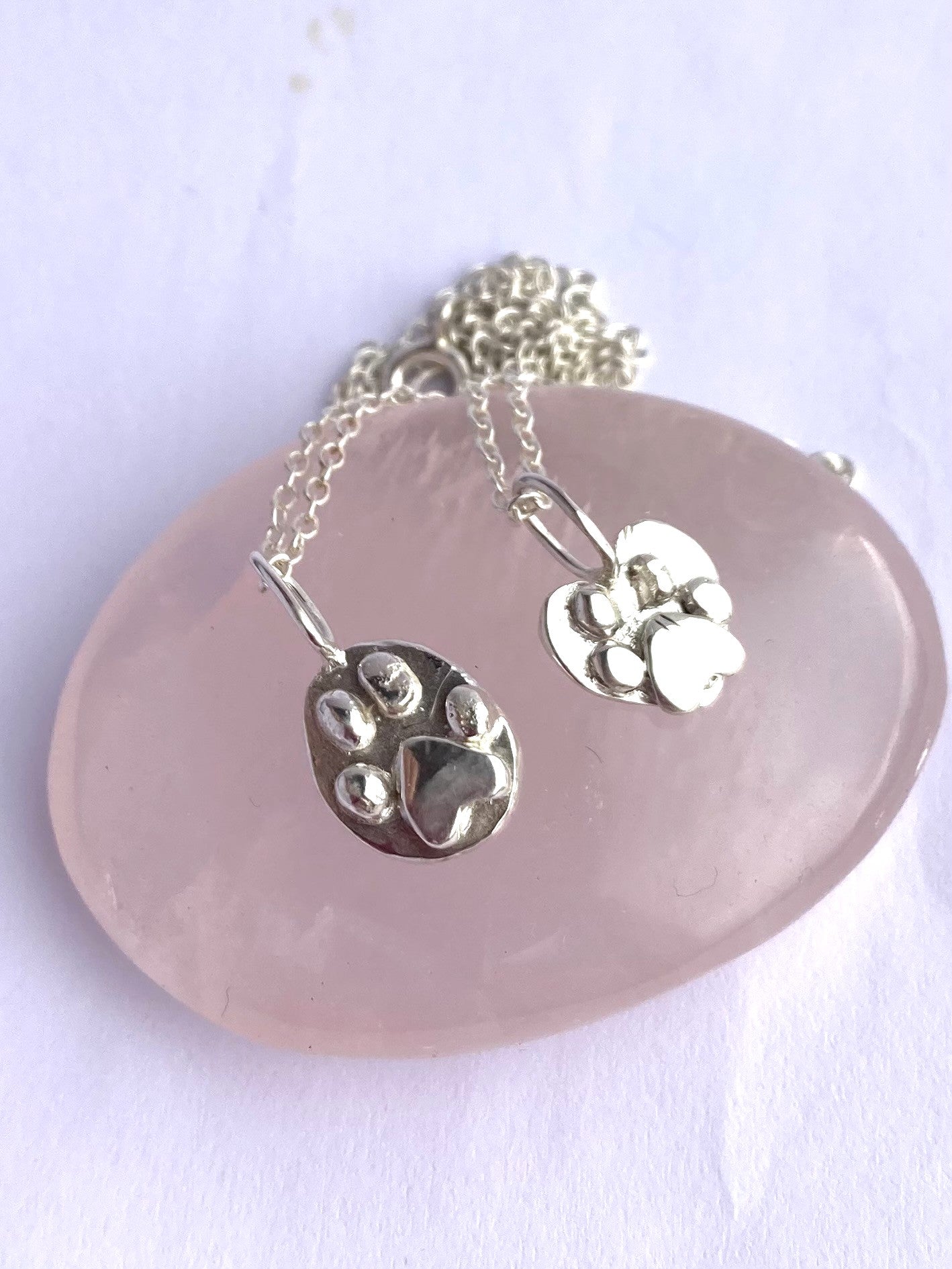 two handmade chunky 3D pawprint pendants by Kim Styles Jewellery, on rose quartz stone