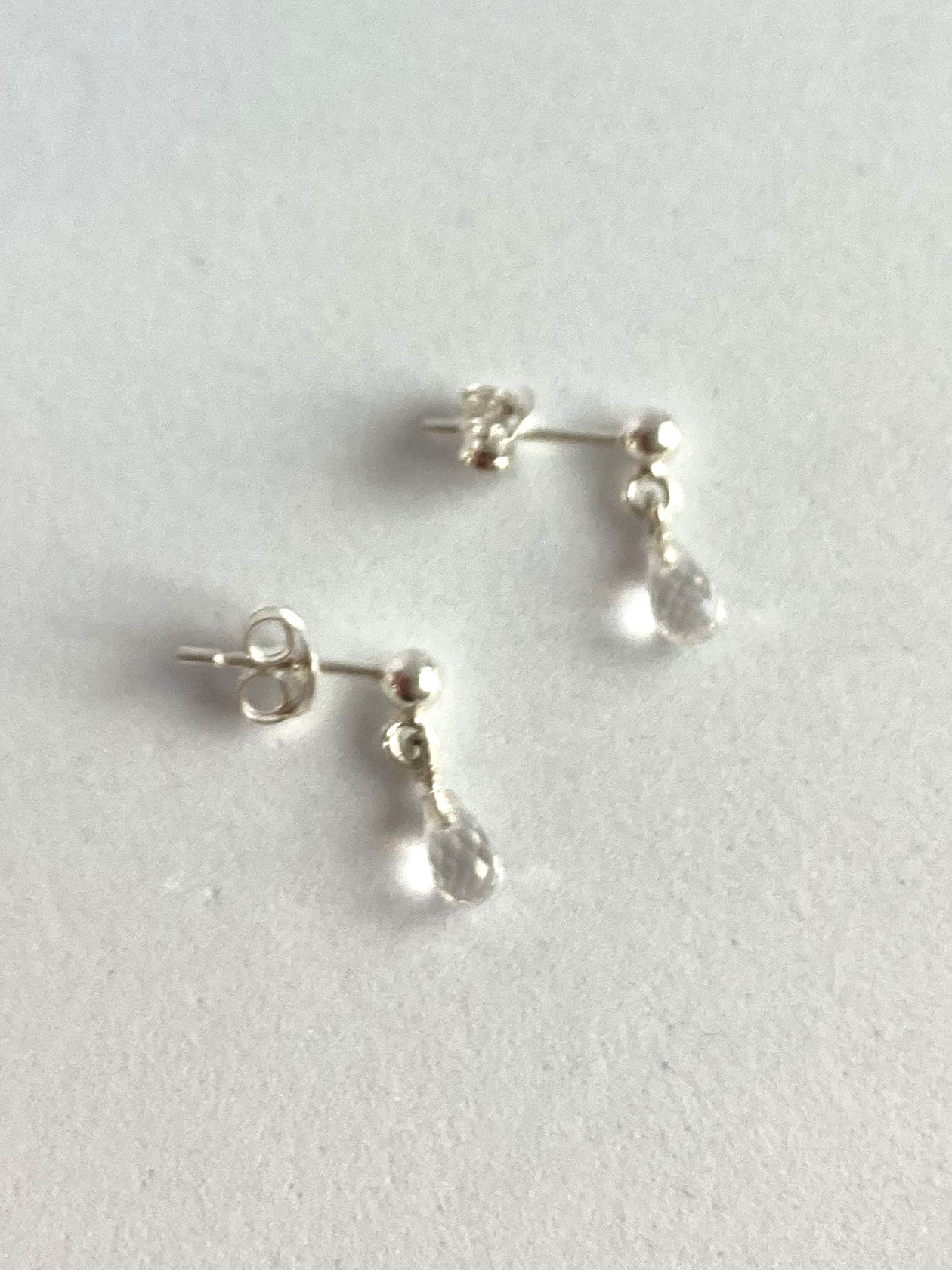 Pair of silver teardrop white topaz earrings on a light grey background