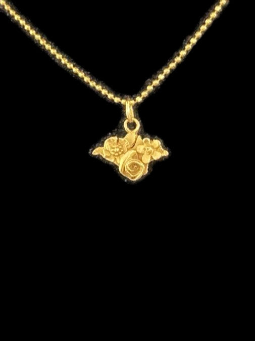 A gold Isle of Wight silhouette necklace with a small floral and leaf pattern, shown against a solid black background, by Kim Styles Jewellery