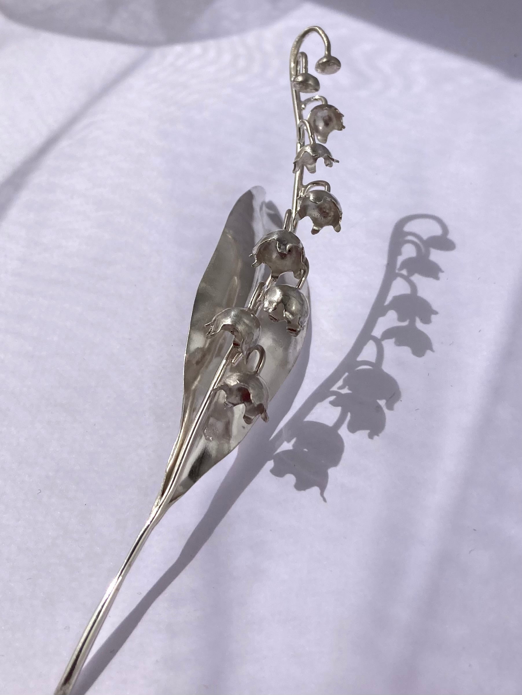 silver handmade lily of the valley sculpture and shadow