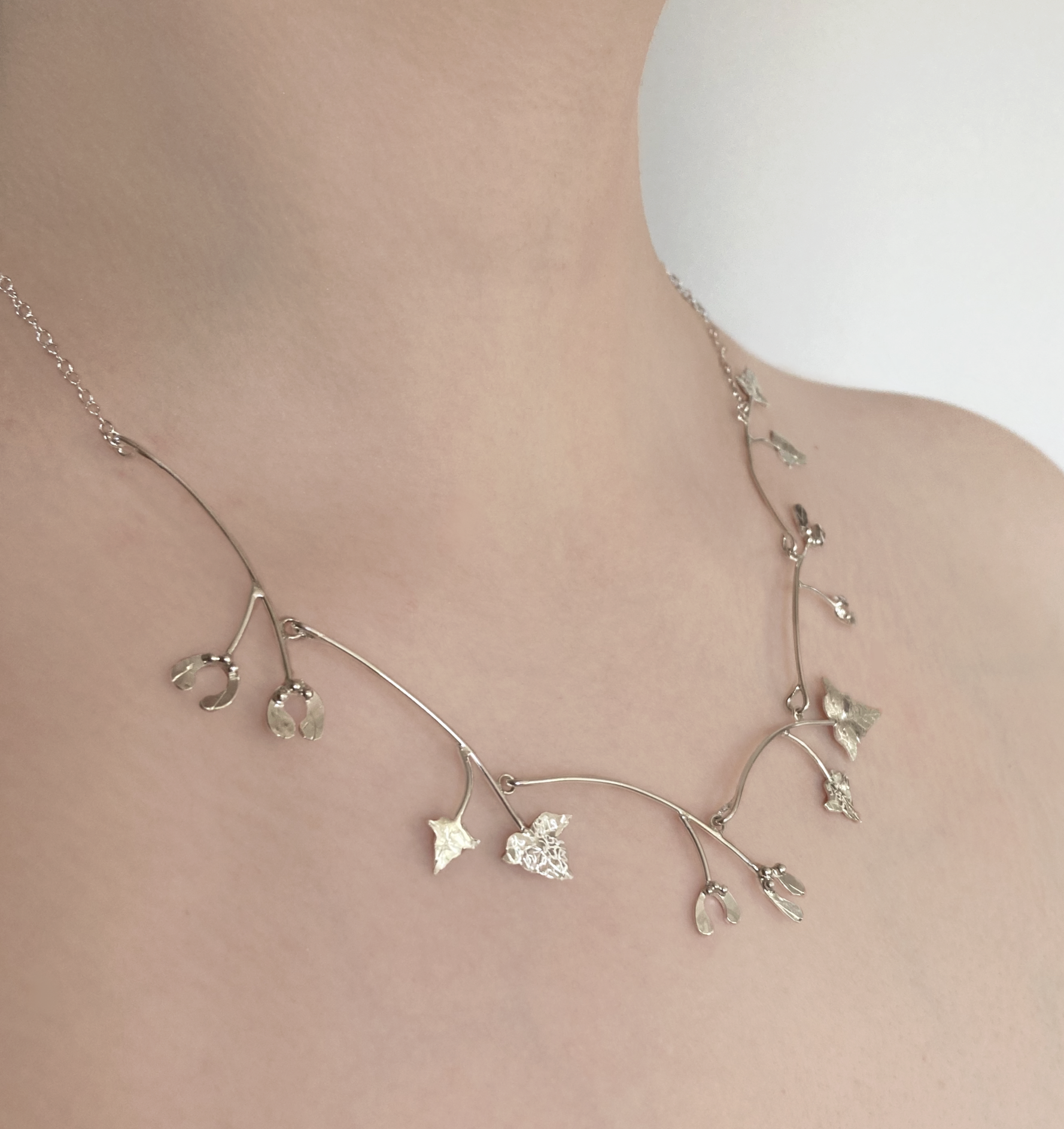 silver handmade floral necklace of mistletoe and vine leaves, worn on neck