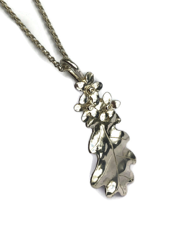 silver handmade oak leaf pendant with forget-me-not flowers on white background